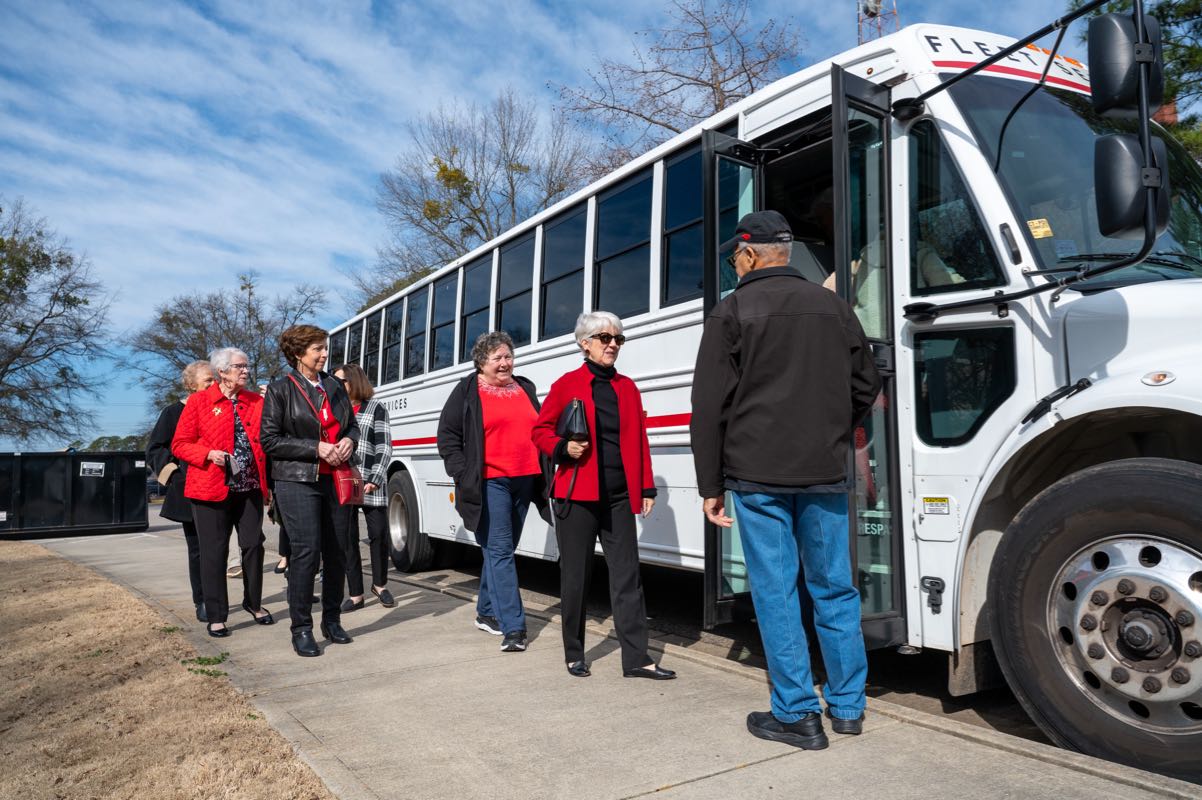 Lifelong learners dressed in red and black board an NC State bus