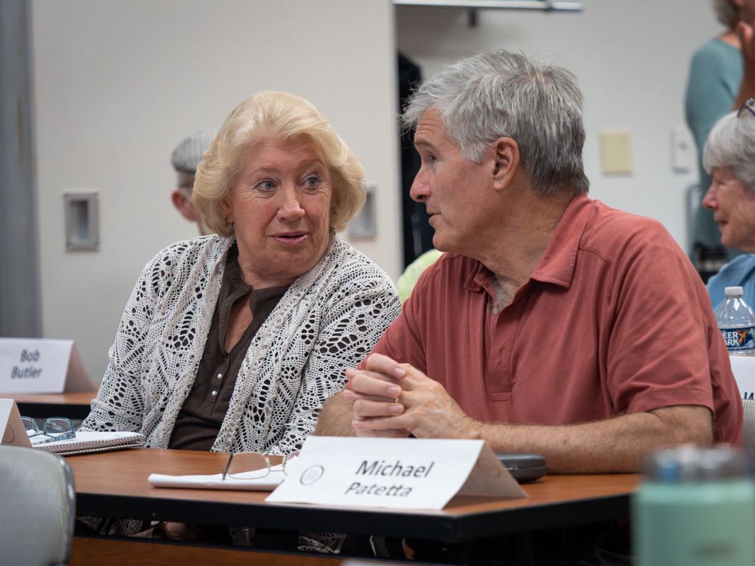 Two lifelong learners converse while sitting at a desk