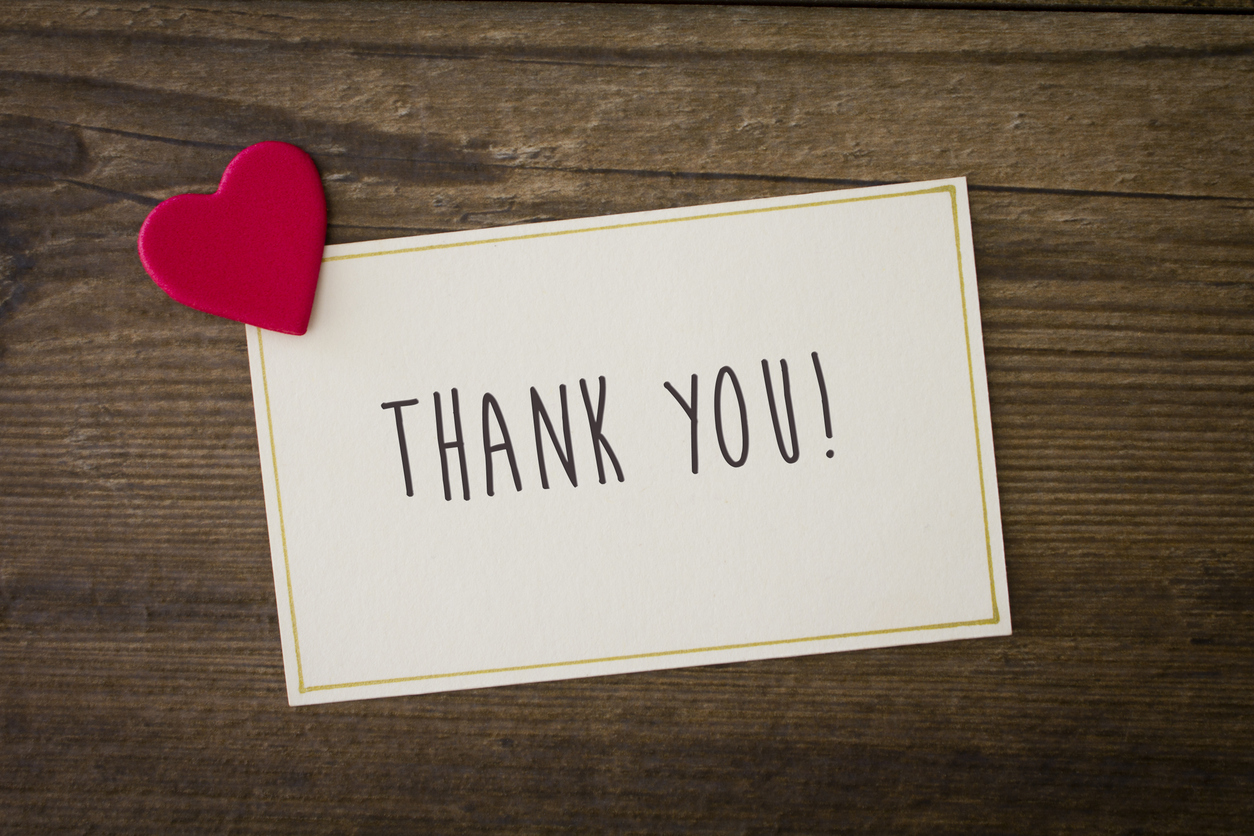 Thank you written on blank card with a small red heart.
